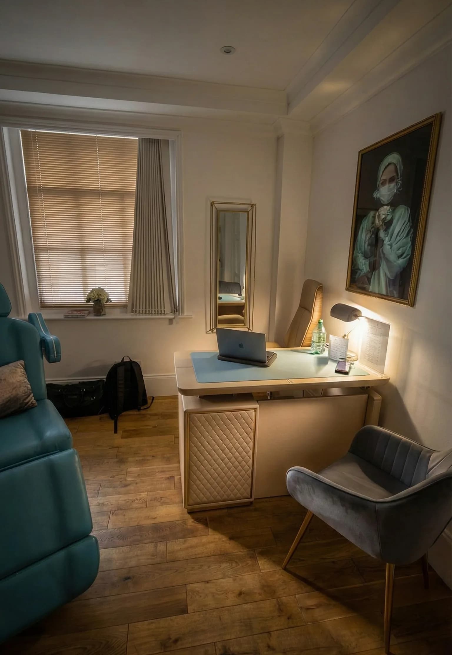 The consultation corner of the LV8 Health London clinic: a desk with an open laptop, an armchair and a second treatment chair by the window